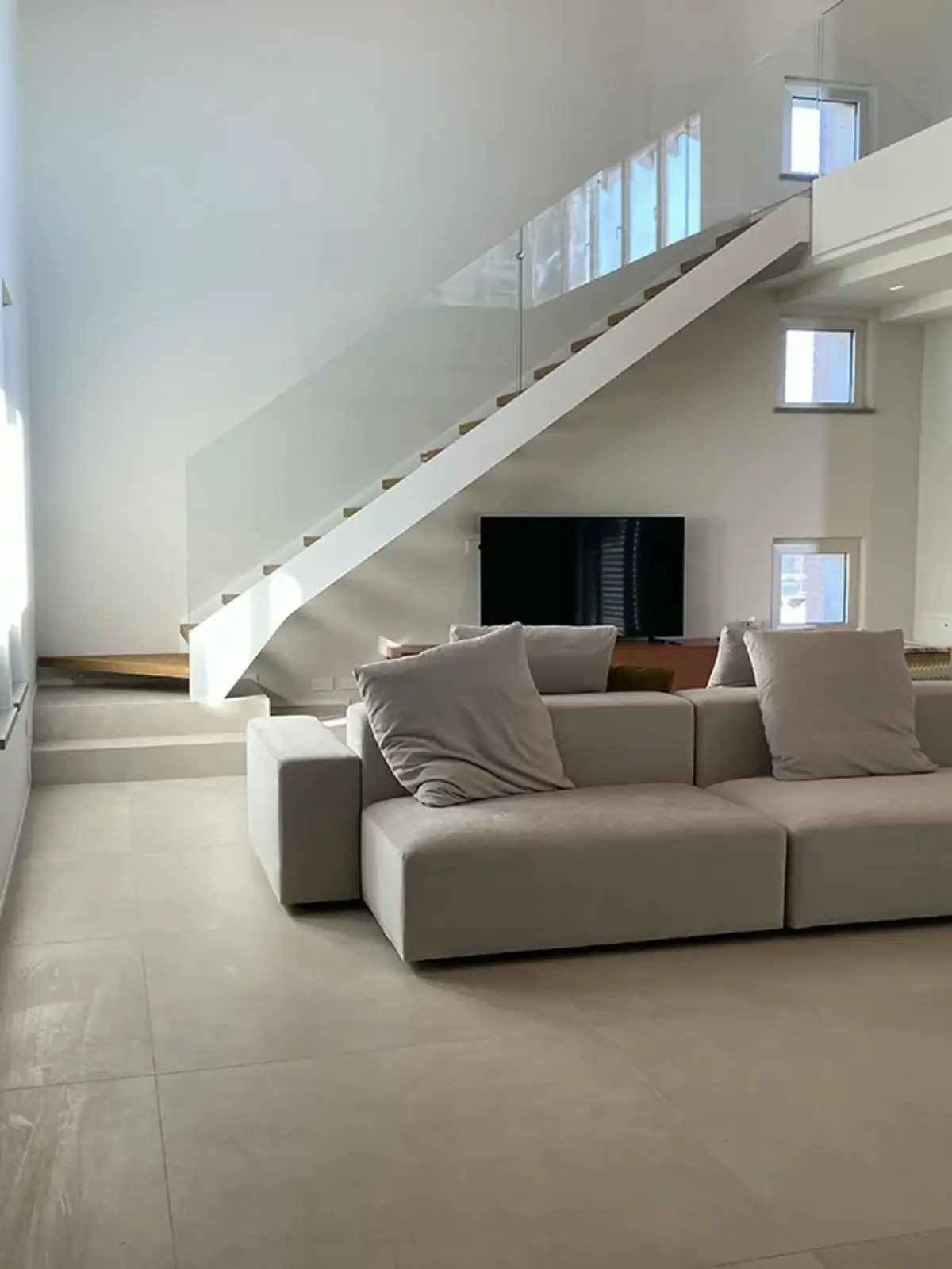 scala lineare con fascioni in acciaio bianco e ringhiera in vetro